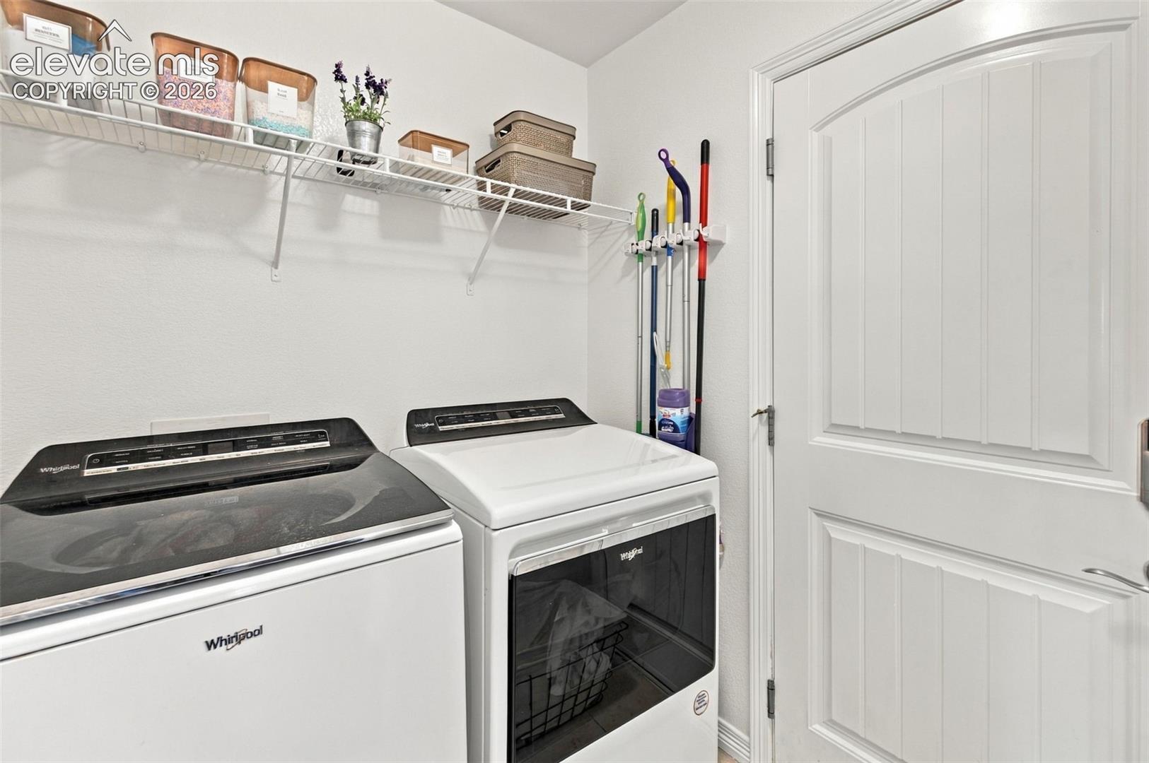 Laundry room featuring a white paneled door, wire shelving, and a wall-mounted organizing rack