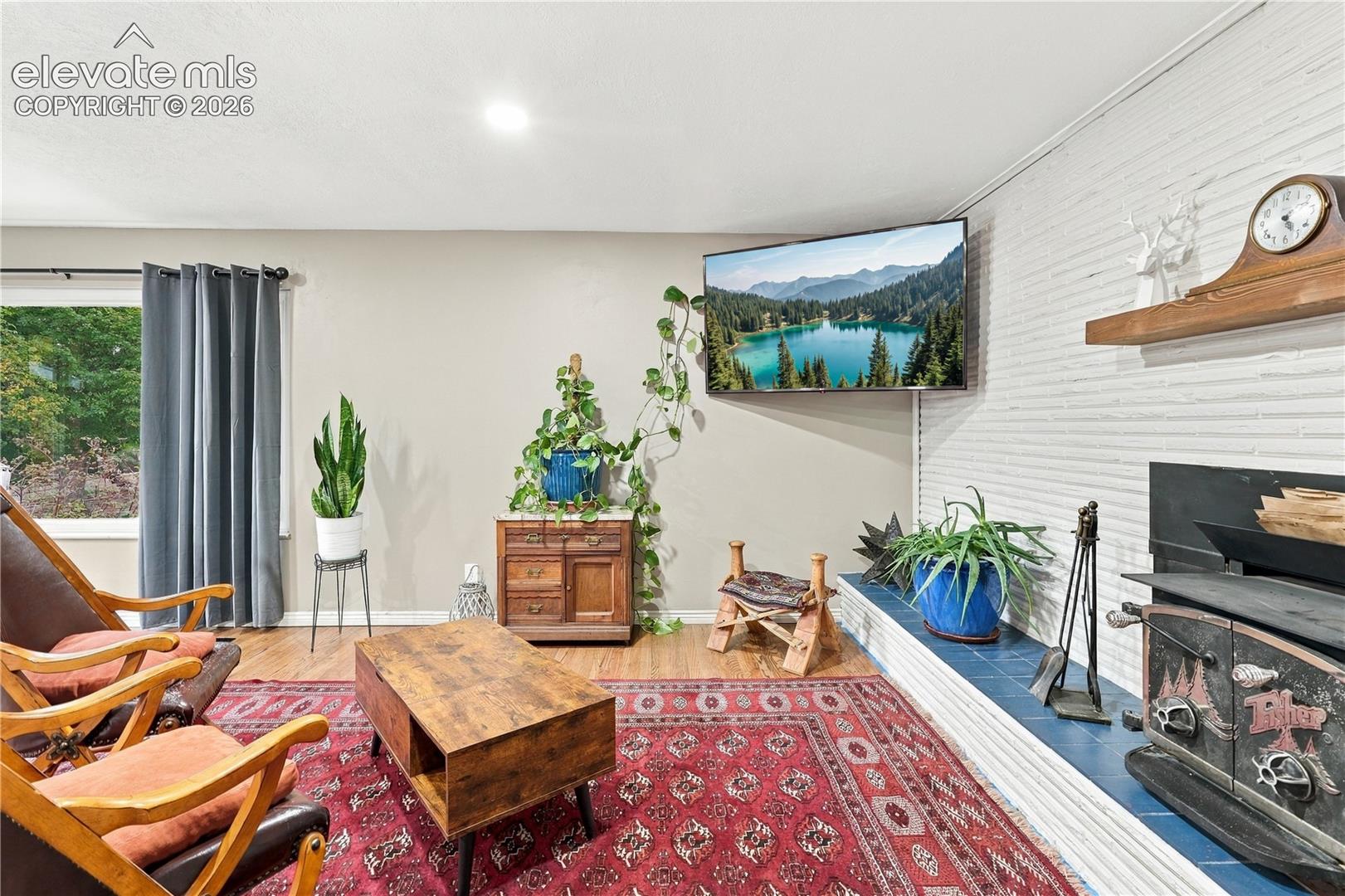 White painted brick fireplace featuring a wood-burning stove, a raised tile hearth, and a wooden mantel