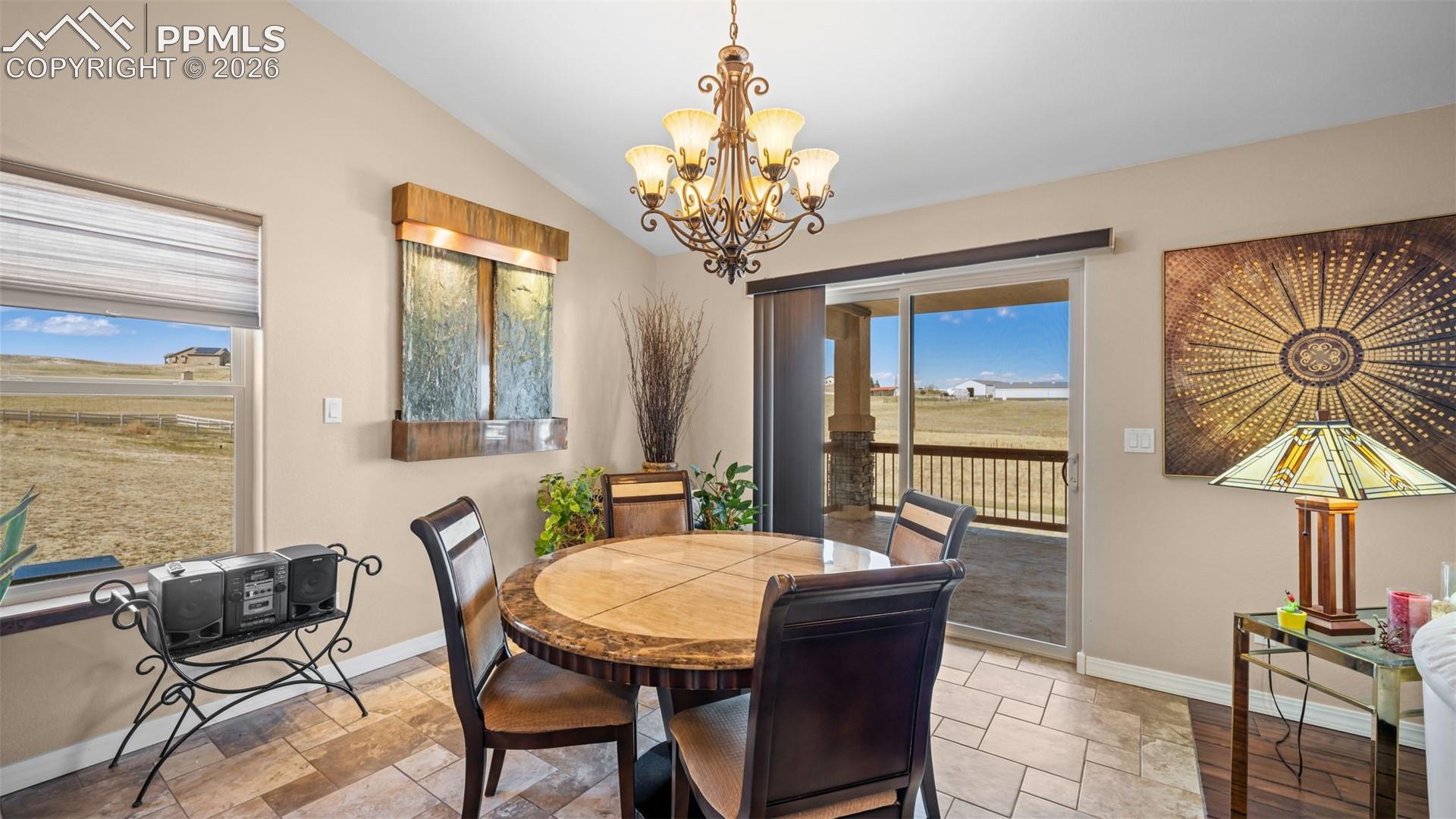 Dining room featuring hanging lights, stone tile flooring, and lofted ceiling, fountain included