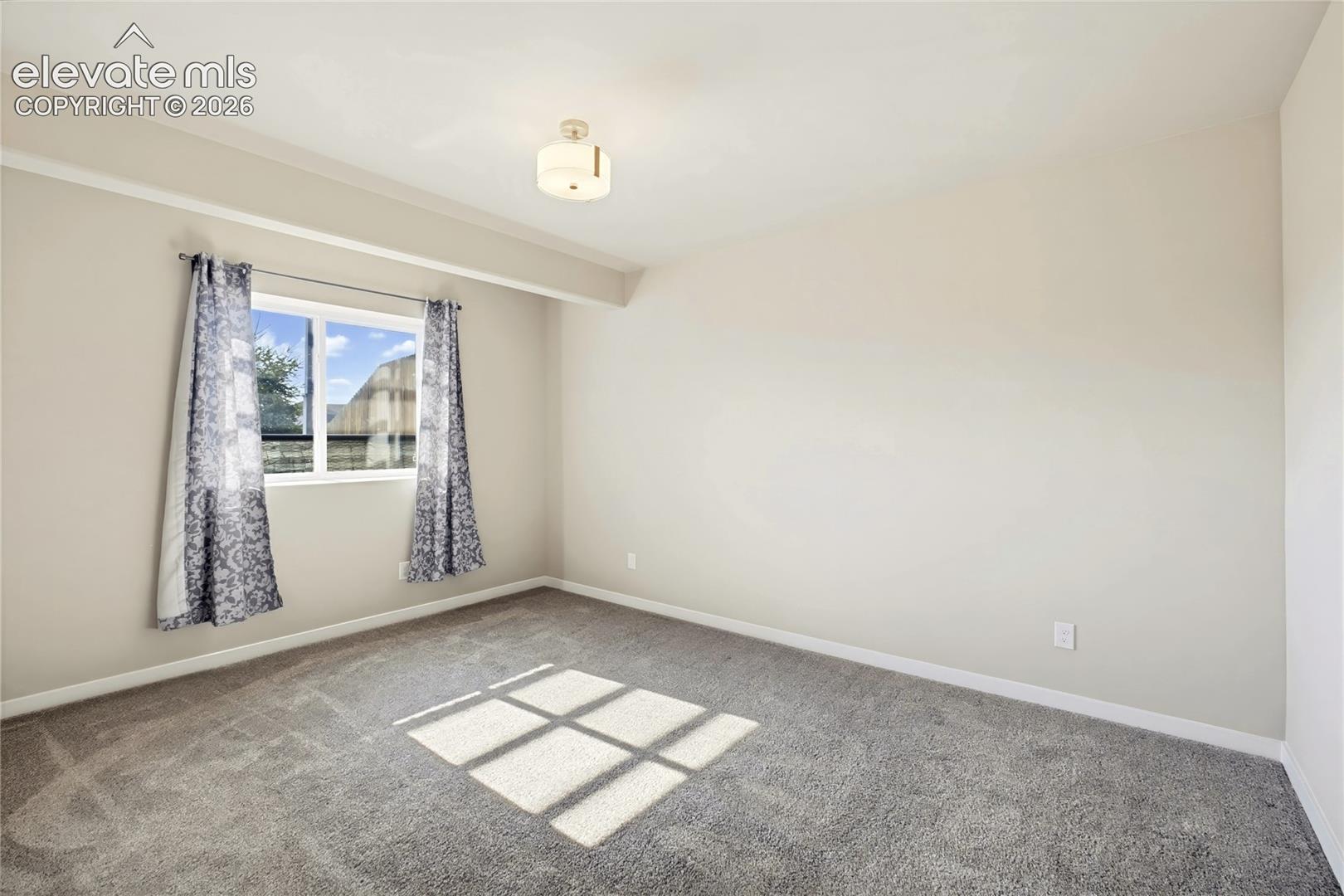 Neutral wall paint, plush carpeting, single-pane window, and a semi-flush mount ceiling fixture