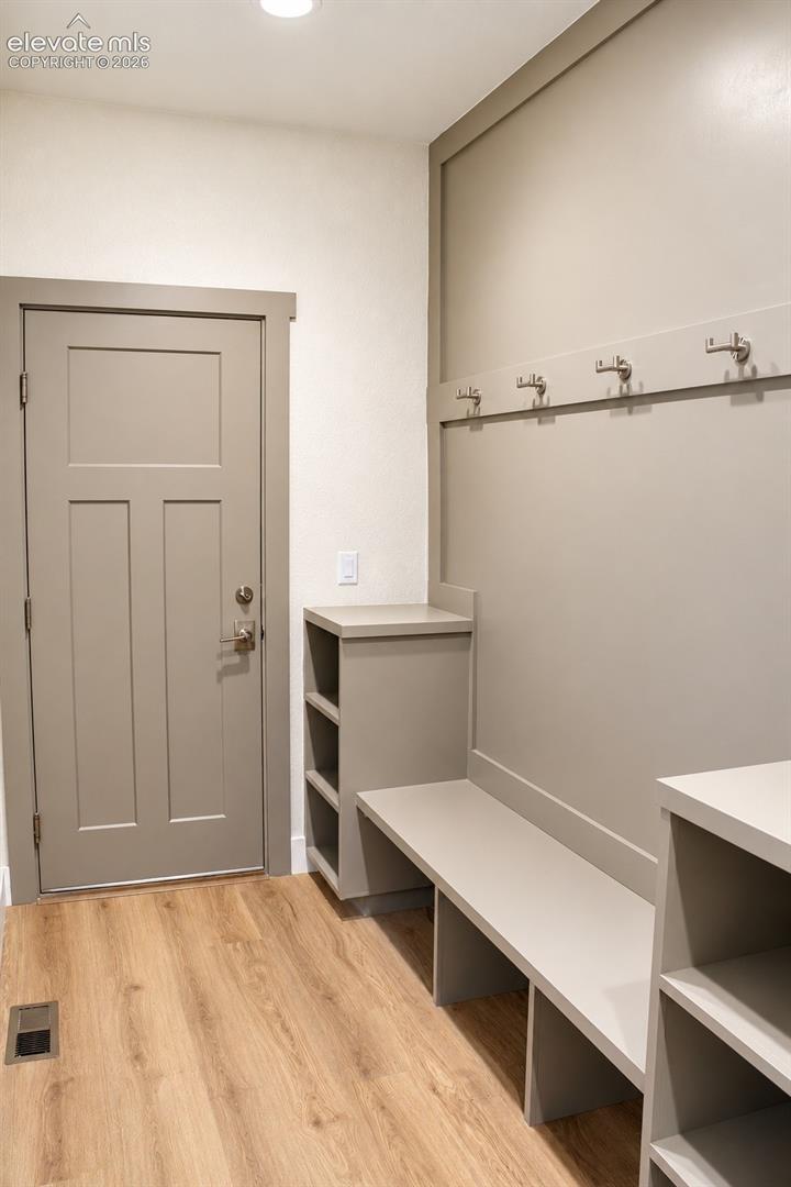 Wood-finish flooring, recessed lighting, and built-in storage bench with shelving and coat hooks