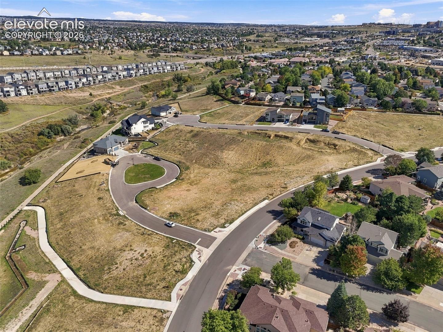 Expansive undeveloped lot featuring a paved cul-de-sac and surrounding residential structures