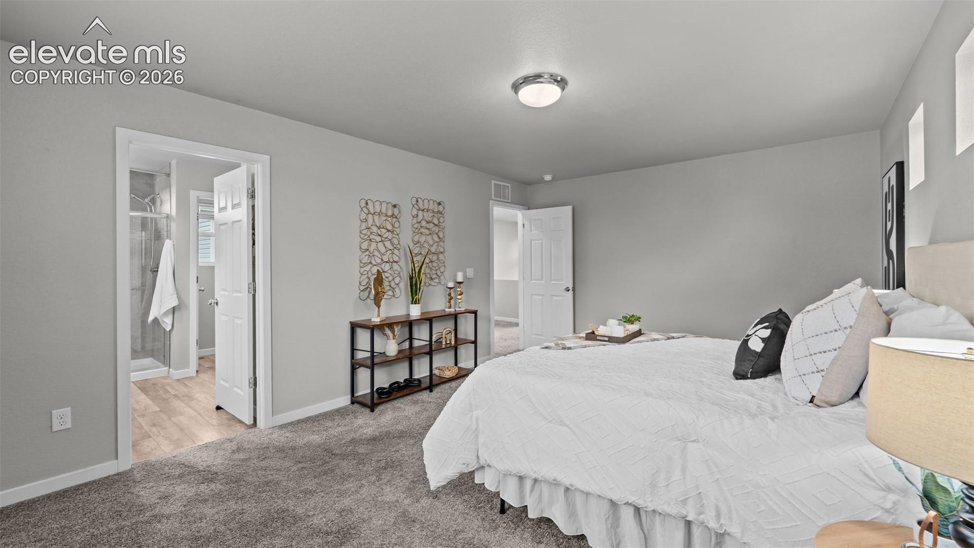 Room featuring neutral-toned carpeting, flush-mount lighting, and solid-core interior doors, with wood-finish flooring visible in the secondary area
