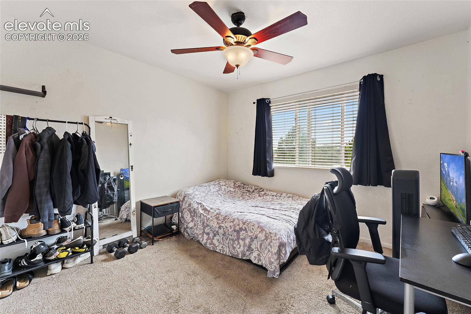 Room featuring neutral carpeting, a central ceiling fan with integrated lighting, and a window with horizontal blinds