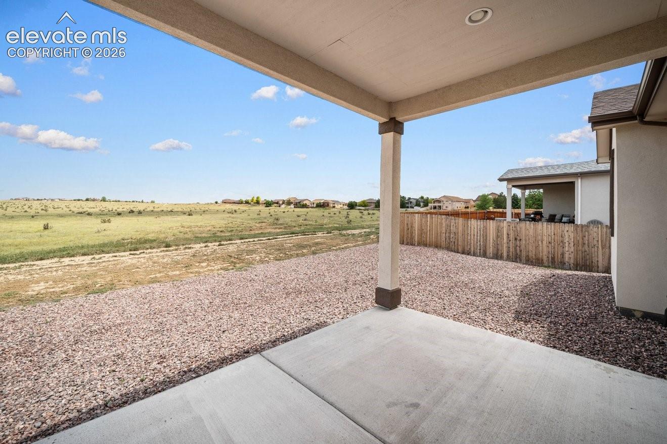 Covered patio with recessed lighting, concrete slab, gravel landscaping, and wood privacy fencing