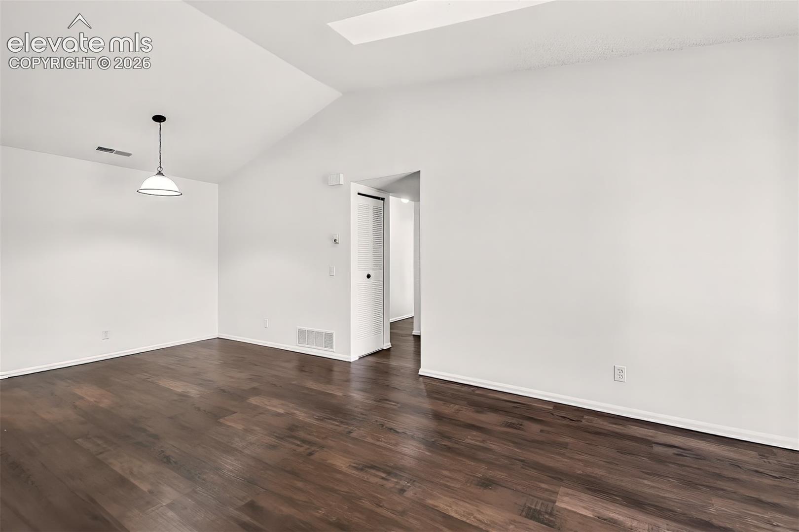 Living room and dining area with vaulted ceilings and skylights. 