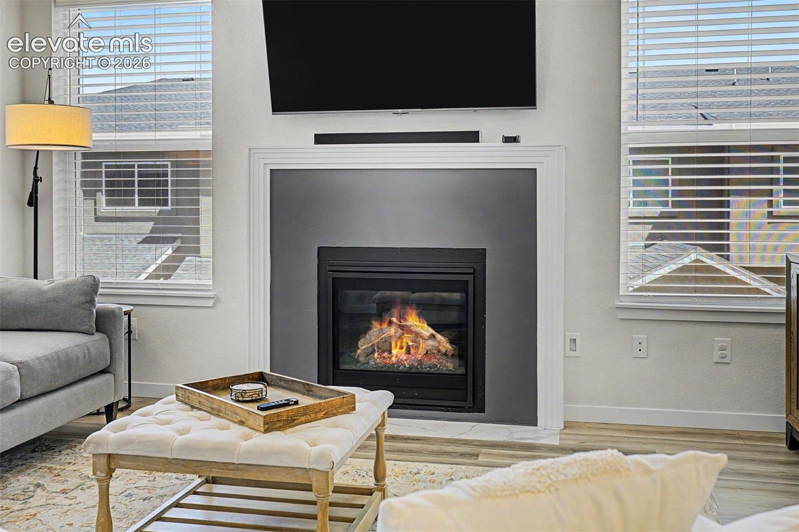 Up close, the gas fireplace reveals its quality — real flame behind mesh screening, a modern matte surround, and a marble-look hearth that together create a focal point worthy of every cozy Colorado evening.