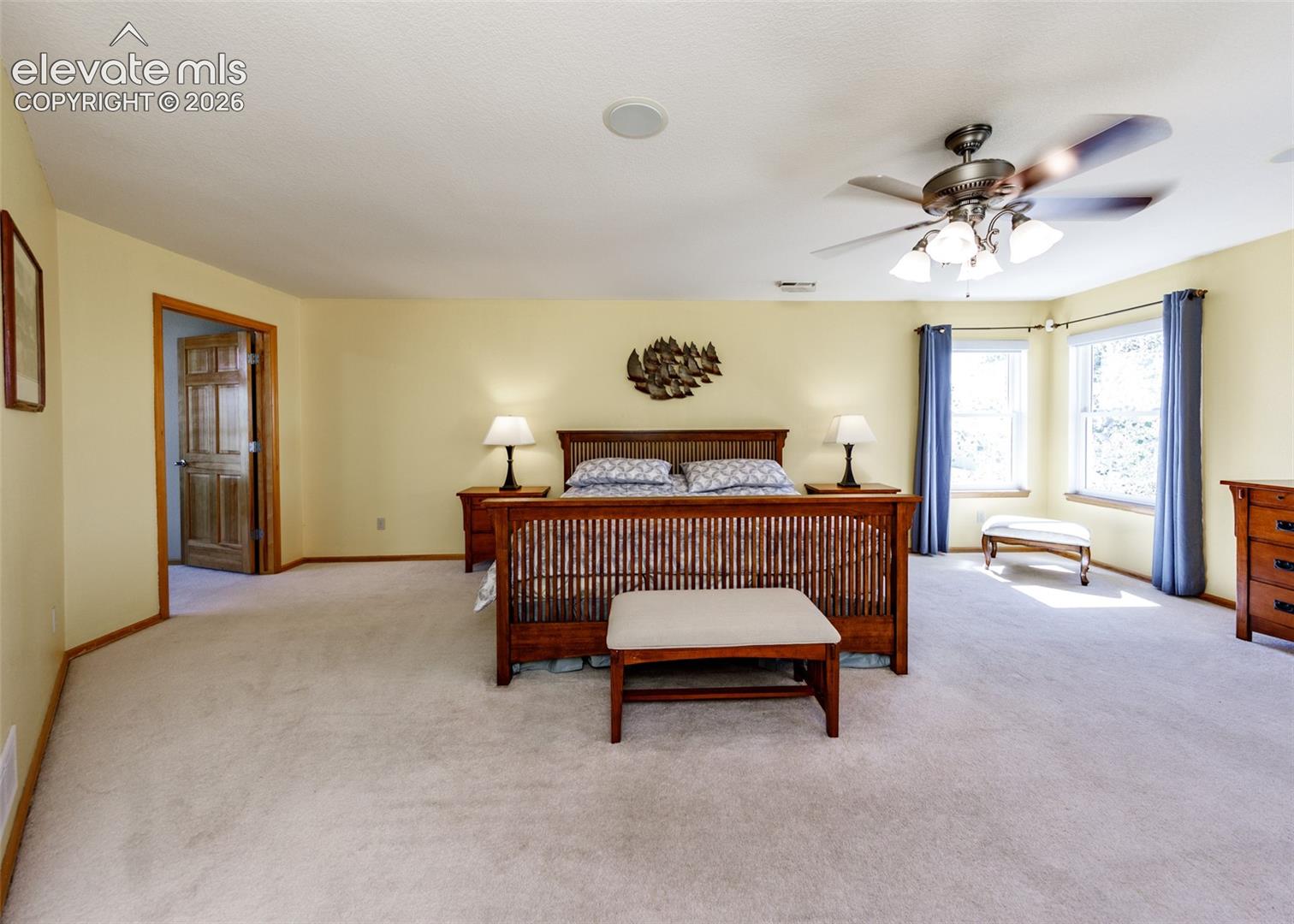 Spacious room with light-colored carpeting, multiple windows, and a ceiling fan with integrated lighting