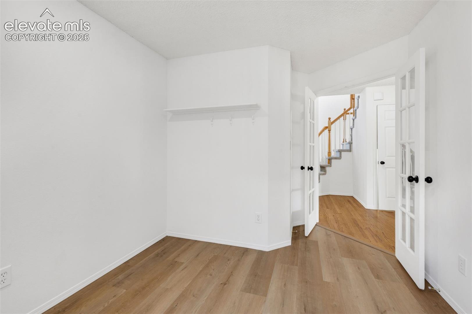 Wood-finish flooring throughout, white walls, and a built-in white shelf
