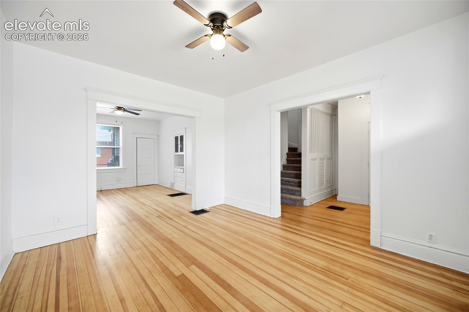 Wood-finish flooring, ceiling fan with integrated lighting, wide cased openings, and built-in cabinetry