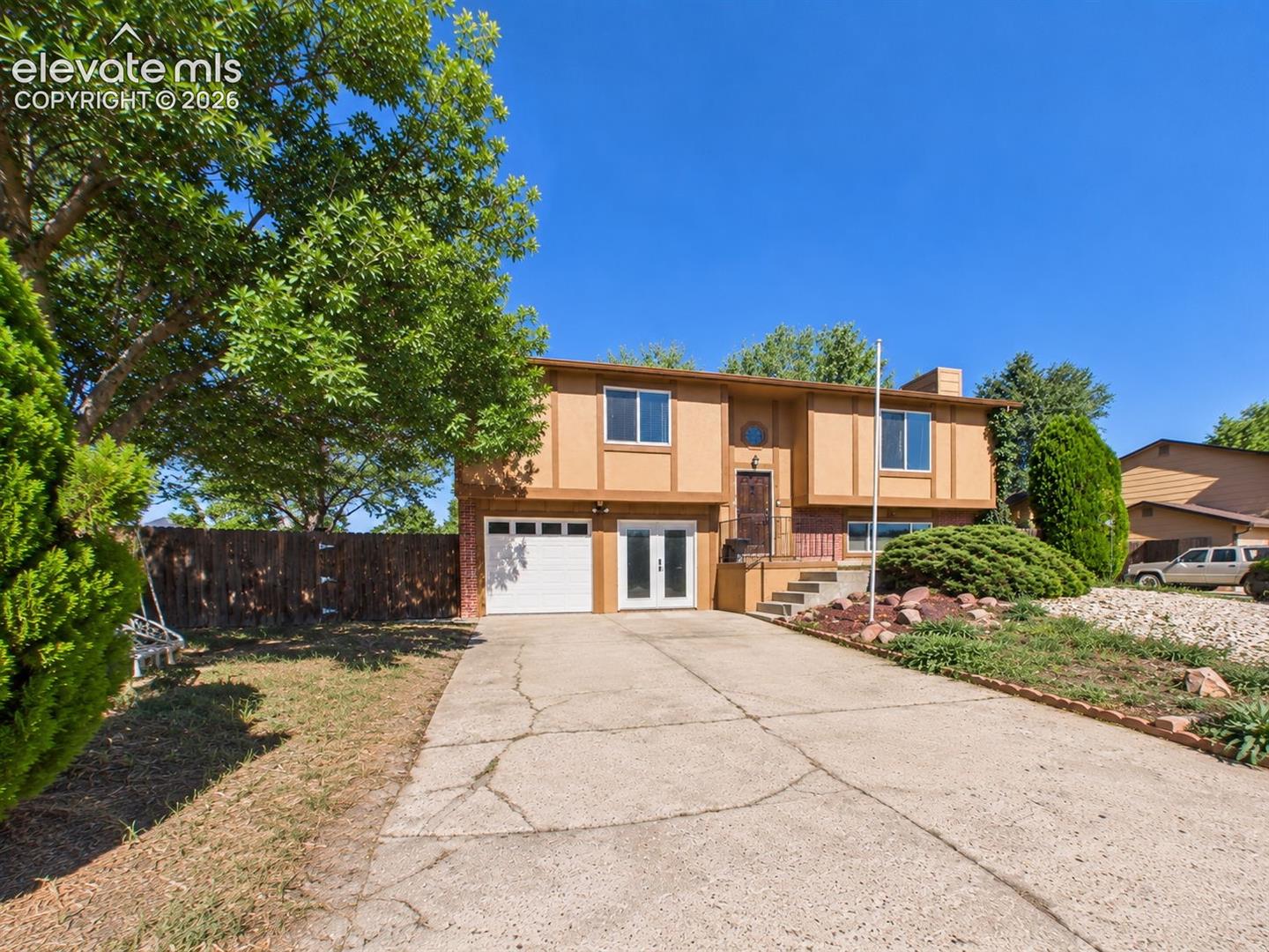 Separate garage provides additional covered parking or workspace, complemented by a wide concrete driveway and fenced side yard.