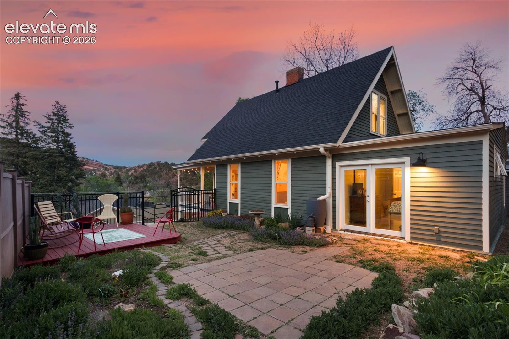 Rear exterior featuring a wood deck, double doors from the primary bedroom, and red rock formations