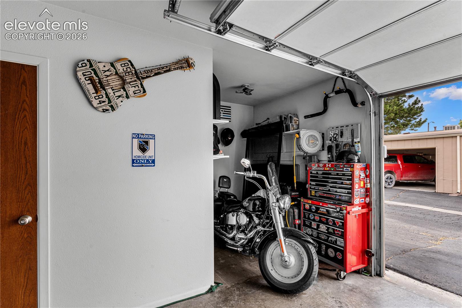 Garage space featuring a metal overhead door, concrete flooring, and exposed structural ceiling track