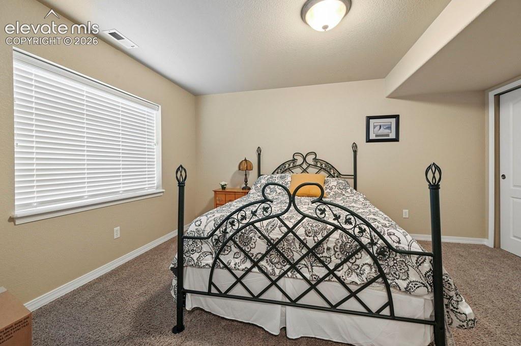 Basement bedroom with neutral wall finishes, white window blinds, recessed lighting, and a bi-fold closet door