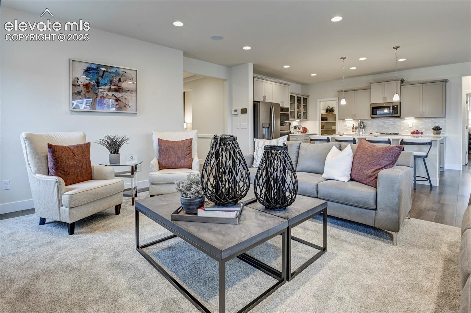 Recessed ceiling lighting, light-toned wall finishes, wood-finish flooring, and light-toned kitchen cabinetry
