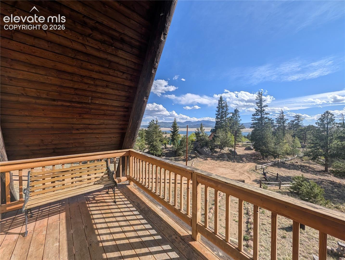 Expansive wood deck with a full wood railing, featuring a sloped wood plank ceiling