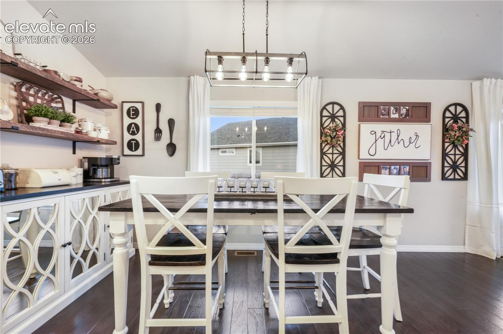 Hardwood-finish flooring, built-in open shelving, and a decorative light fixture illuminate the dining area