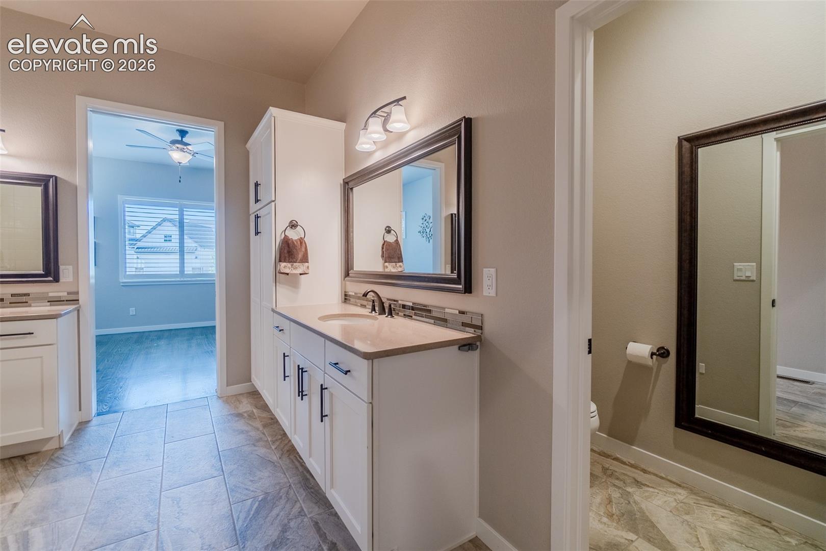 Double vanity with white cabinetry, light countertops, and dark bronze hardware