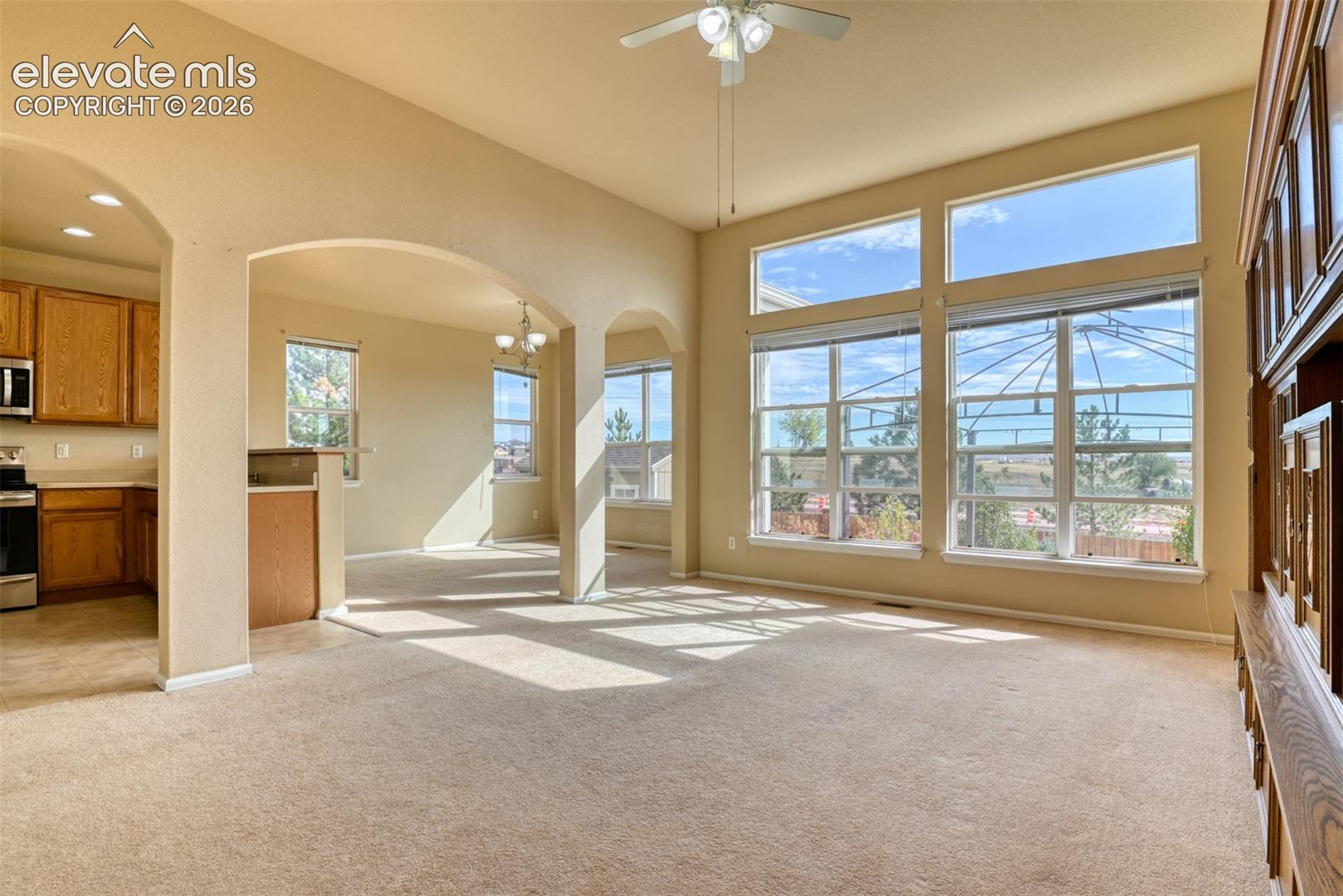 Vaulted ceilings, large transom windows, built-in wooden media cabinetry, and architectural arched wall openings