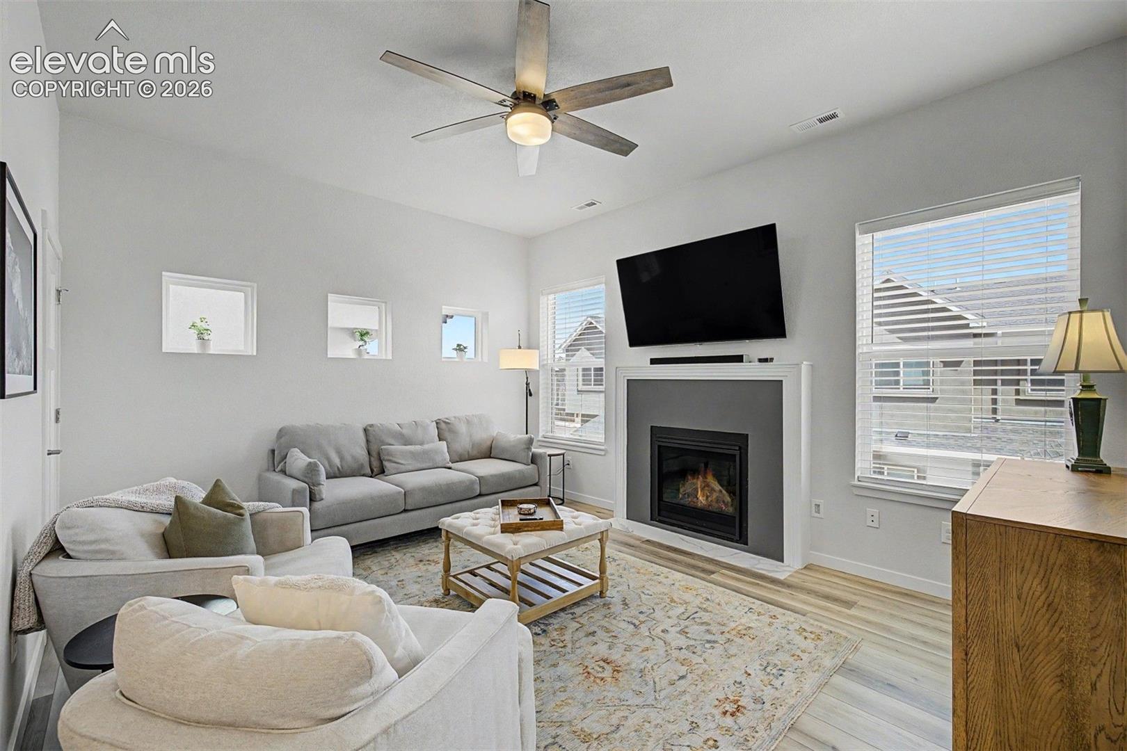 The living room is the heart of the home, anchored by a modern gas fireplace with a sleek surround, where plush sofas and a tufted ottoman invite you to settle in for an evening.