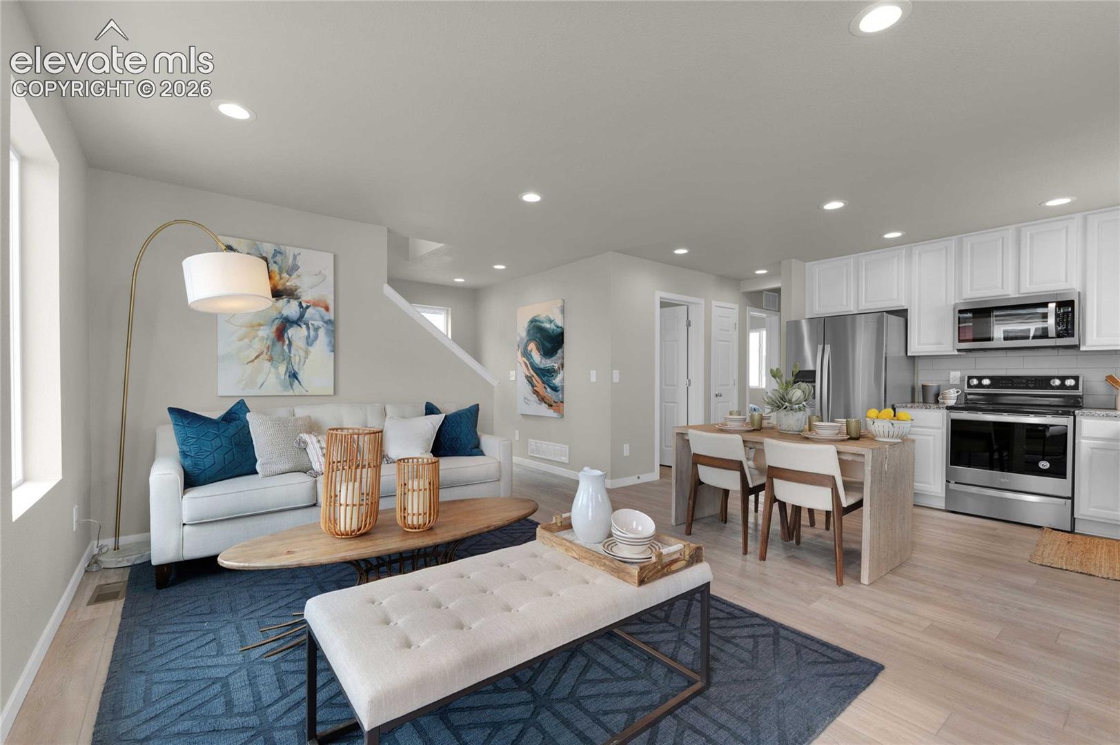 Open-concept living space featuring wood-finish flooring, recessed lighting, white cabinetry, a kitchen island, and stainless steel appliances
*photos of a model home*