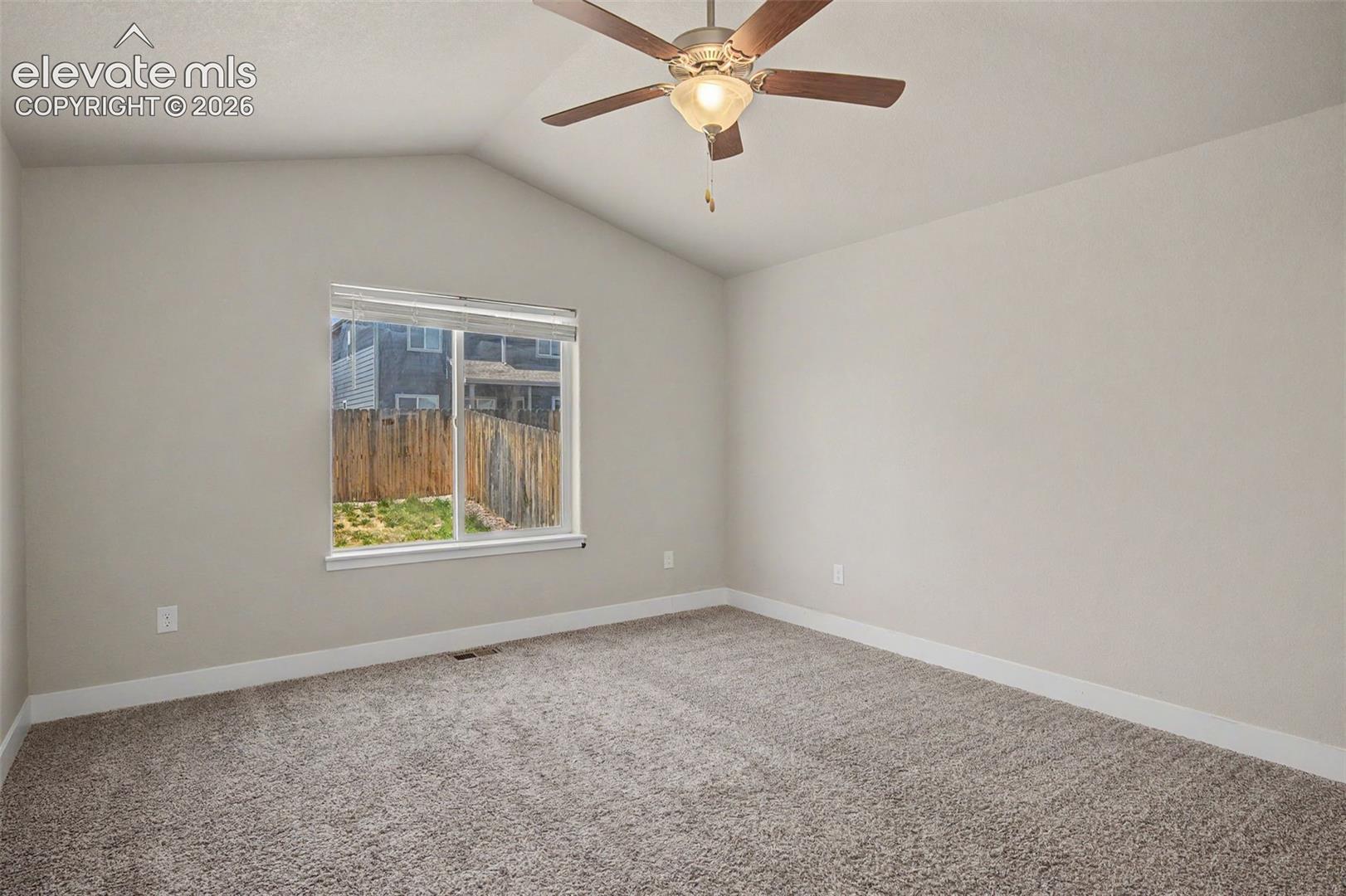 Carpeted room featuring a vaulted ceiling and a ceiling fan with integrated lighting