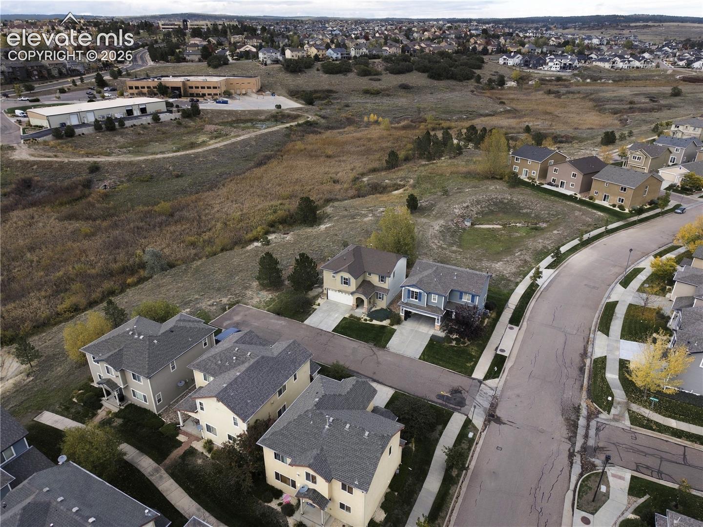 Aerial perspective of a residential neighborhood featuring multi-story dwellings, paved roadways, sidewalk infrastructure, and expansive open space