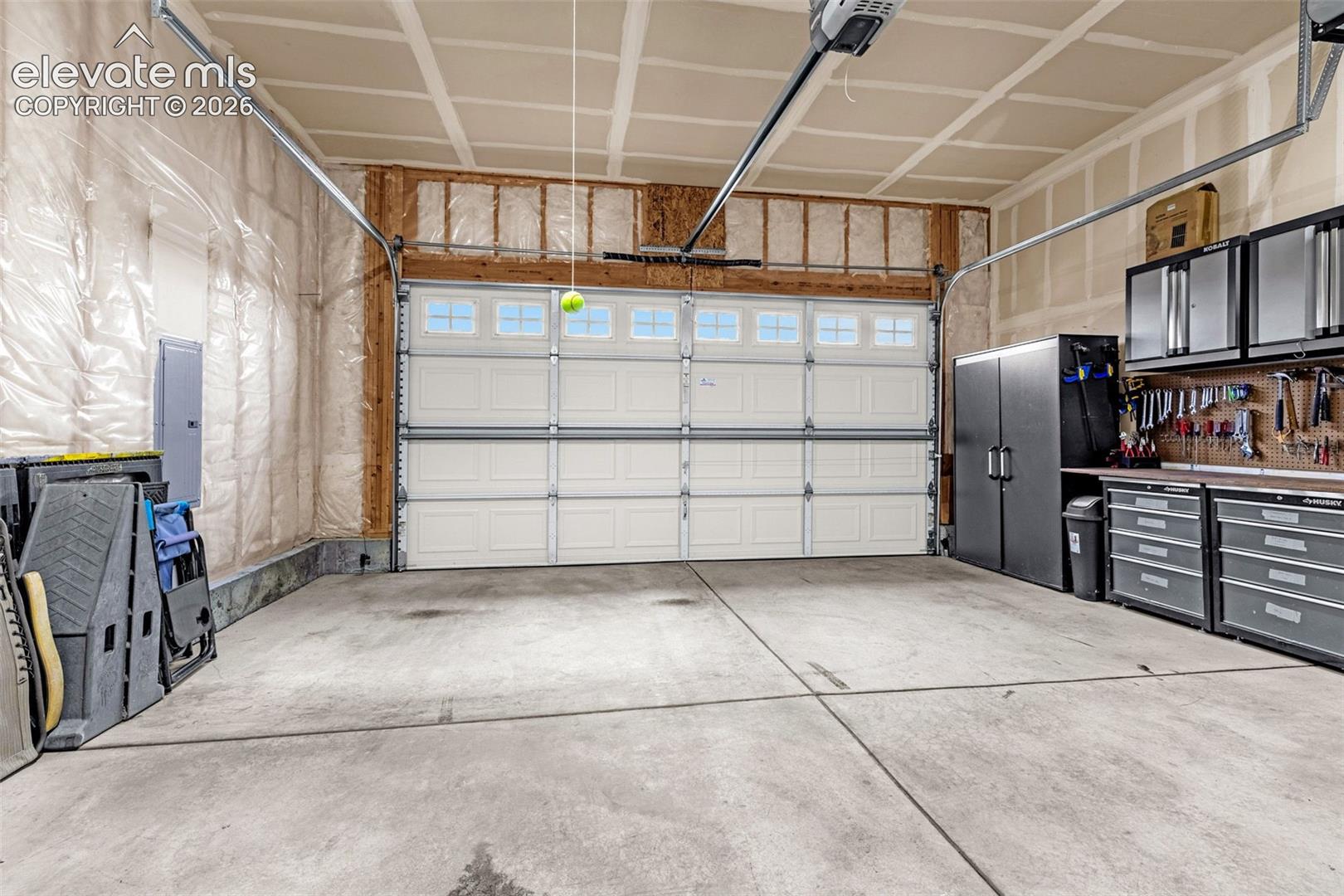 Attached two-car garage featuring a sectional door with windows, concrete flooring, and built-in metal cabinetry