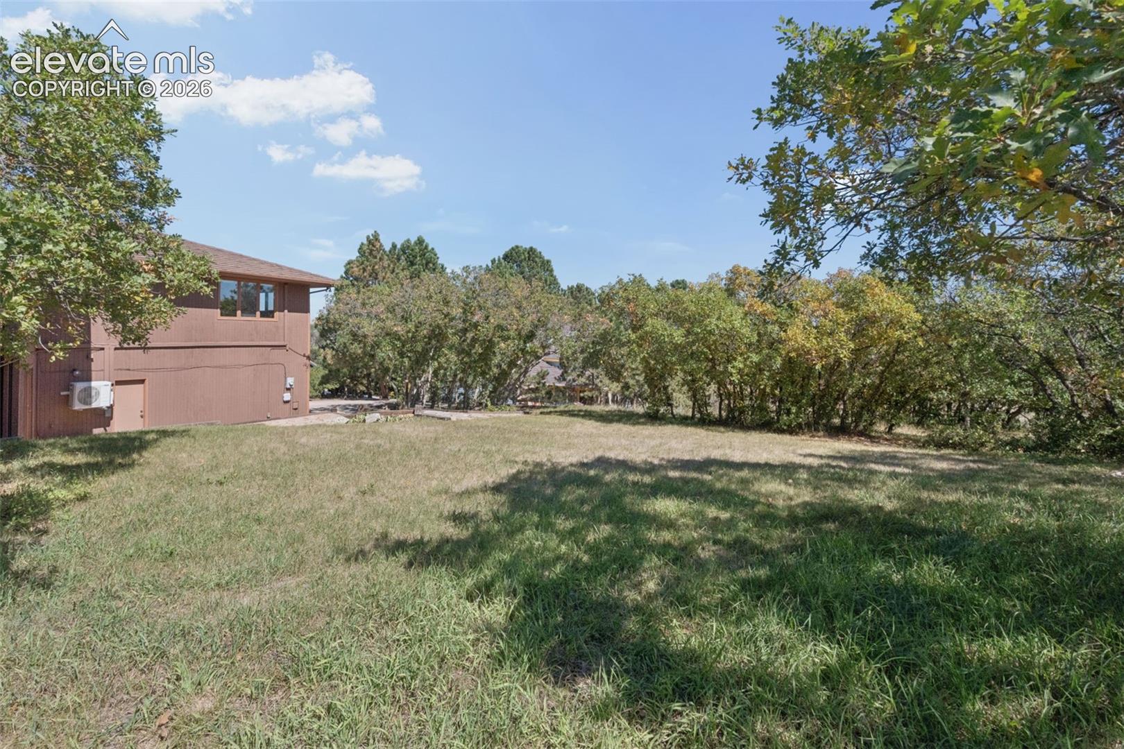 Expansive green lawn with mature trees and a brown exterior structure
