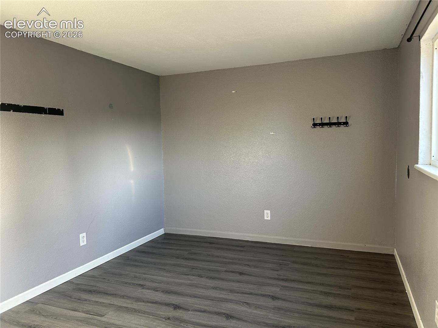 Neutral-toned interior space featuring wood-finish flooring and a single window
