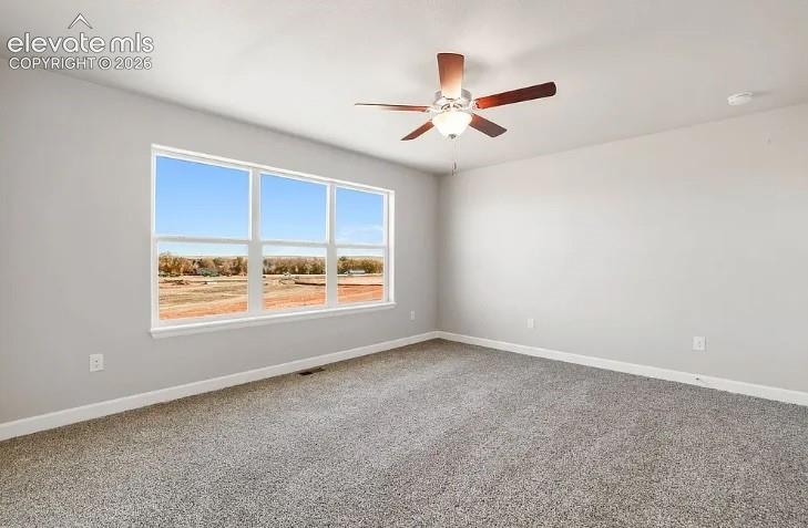 Neutral-toned interior space featuring wall-to-wall carpeting, a multi-pane window, and a ceiling fan with integrated lighting