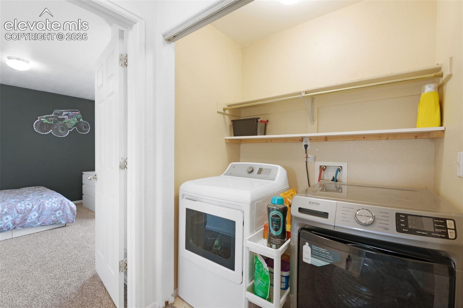 Dedicated laundry closet featuring upper shelving and utility hookups