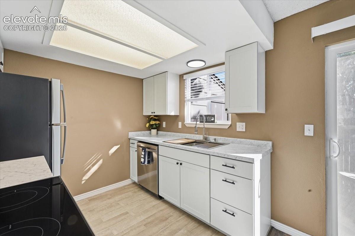 Kitchen featuring white cabinetry, light countertops, wood-finish flooring, stainless steel appliances, and a sliding glass door