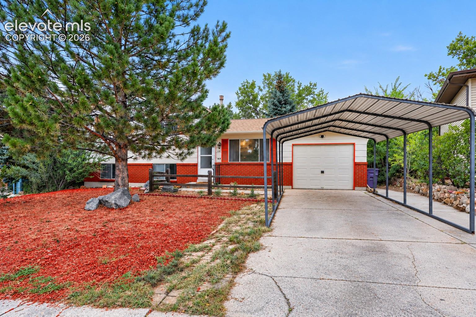 Red brick lower exterior, light-colored upper exterior, attached garage, covered carport, and mature front yard tree