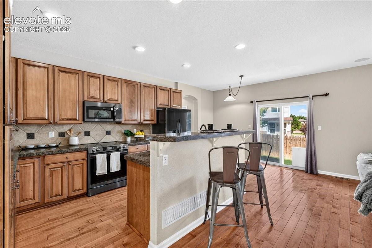 Hardwood-finish flooring, recessed lighting, and a kitchen featuring wood cabinetry