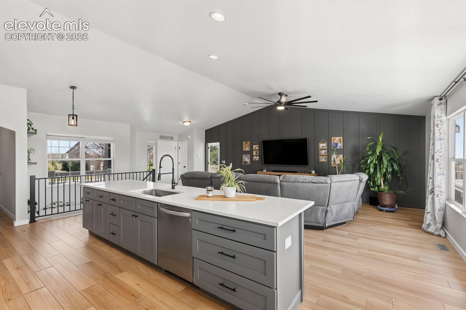 Spacious kitchen island with gray cabinetry, white countertop, and integrated sink with a black gooseneck faucet