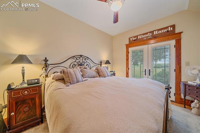 Bedroom with french doors, access to exterior, vaulted ceiling, and a ceiling fan