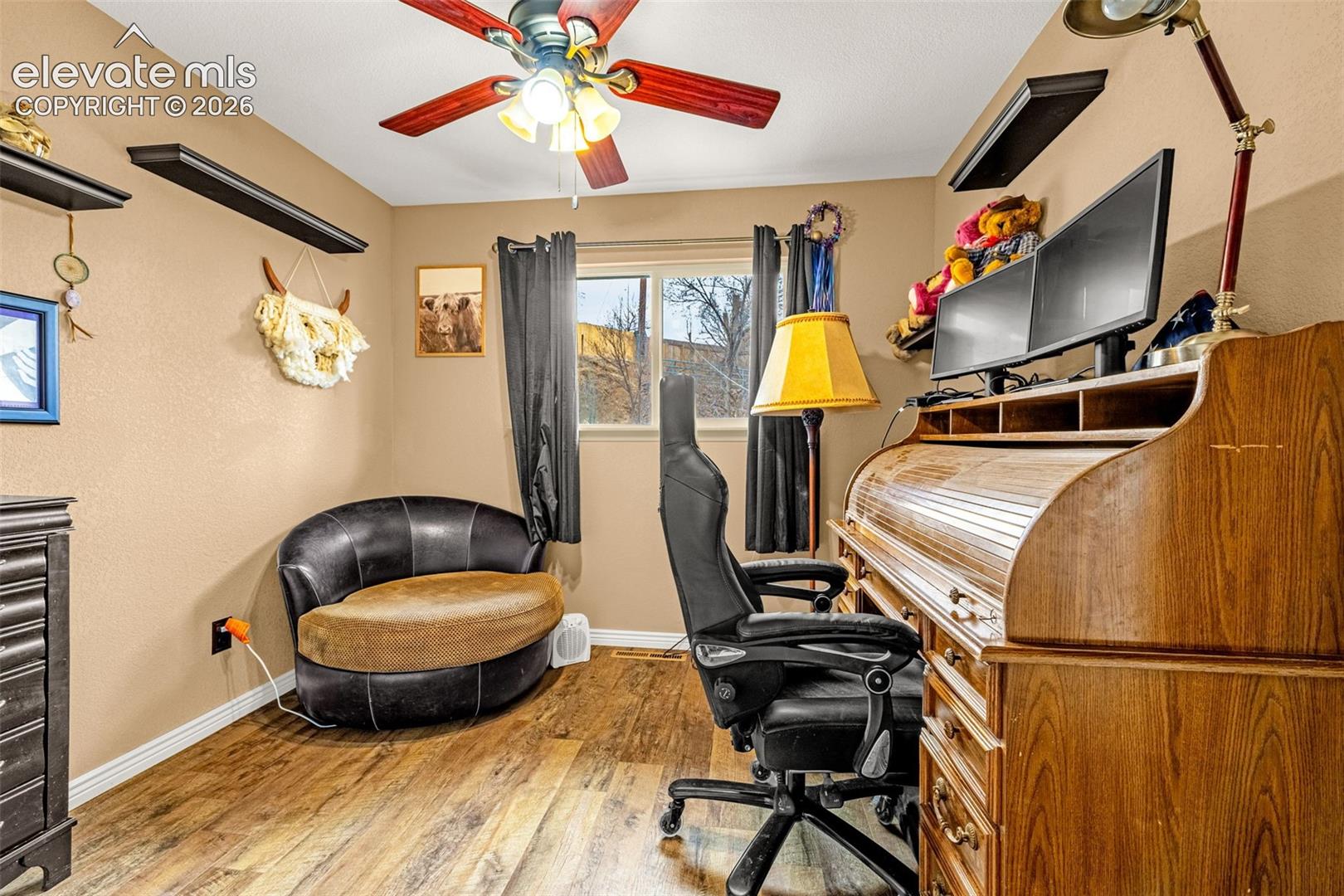 Wood-finish flooring, ceiling fan with integrated lighting, and floating wall-mounted shelving