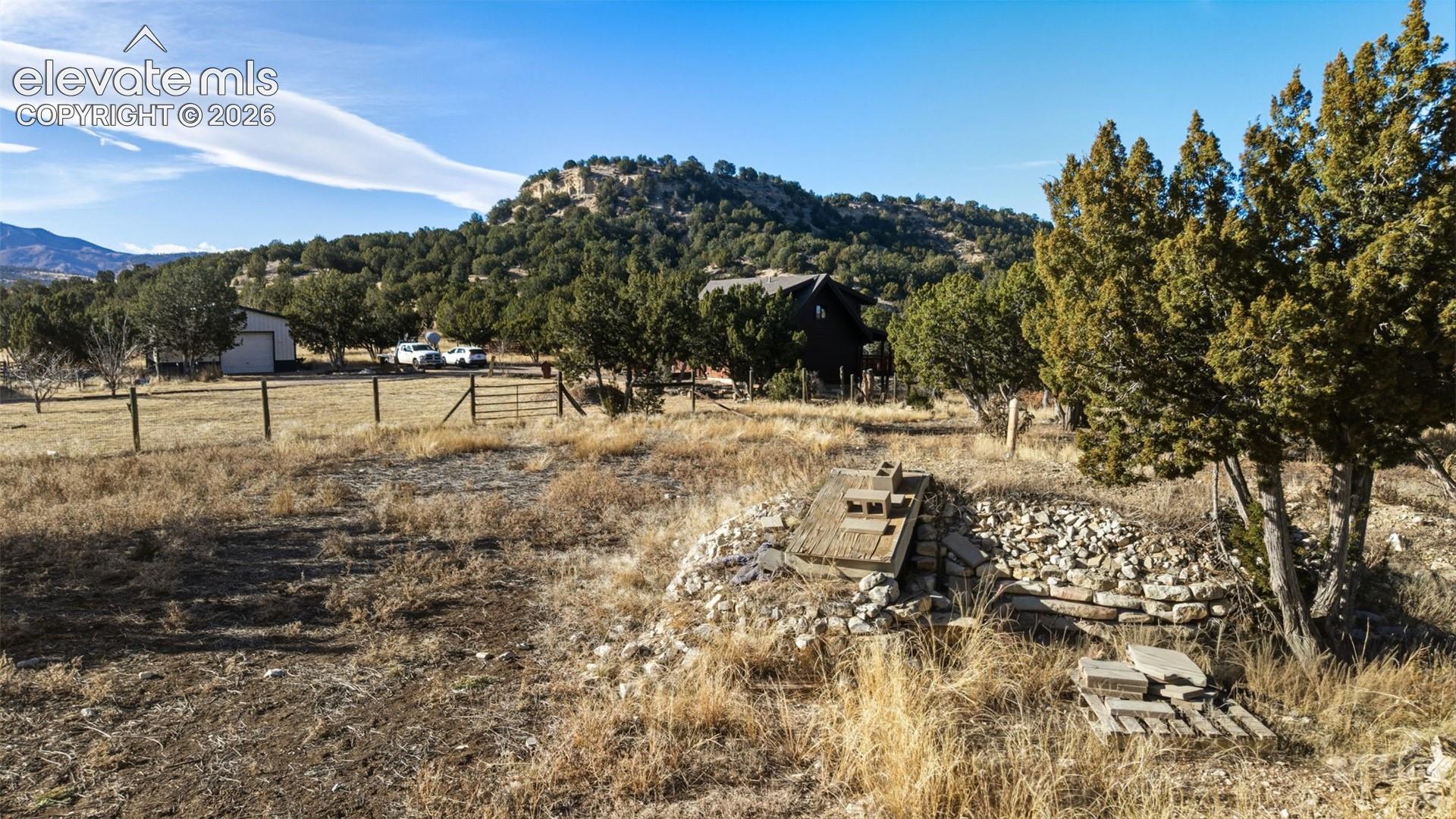 Expansive property with natural landscaping, distant mountain backdrop, and wooded areas