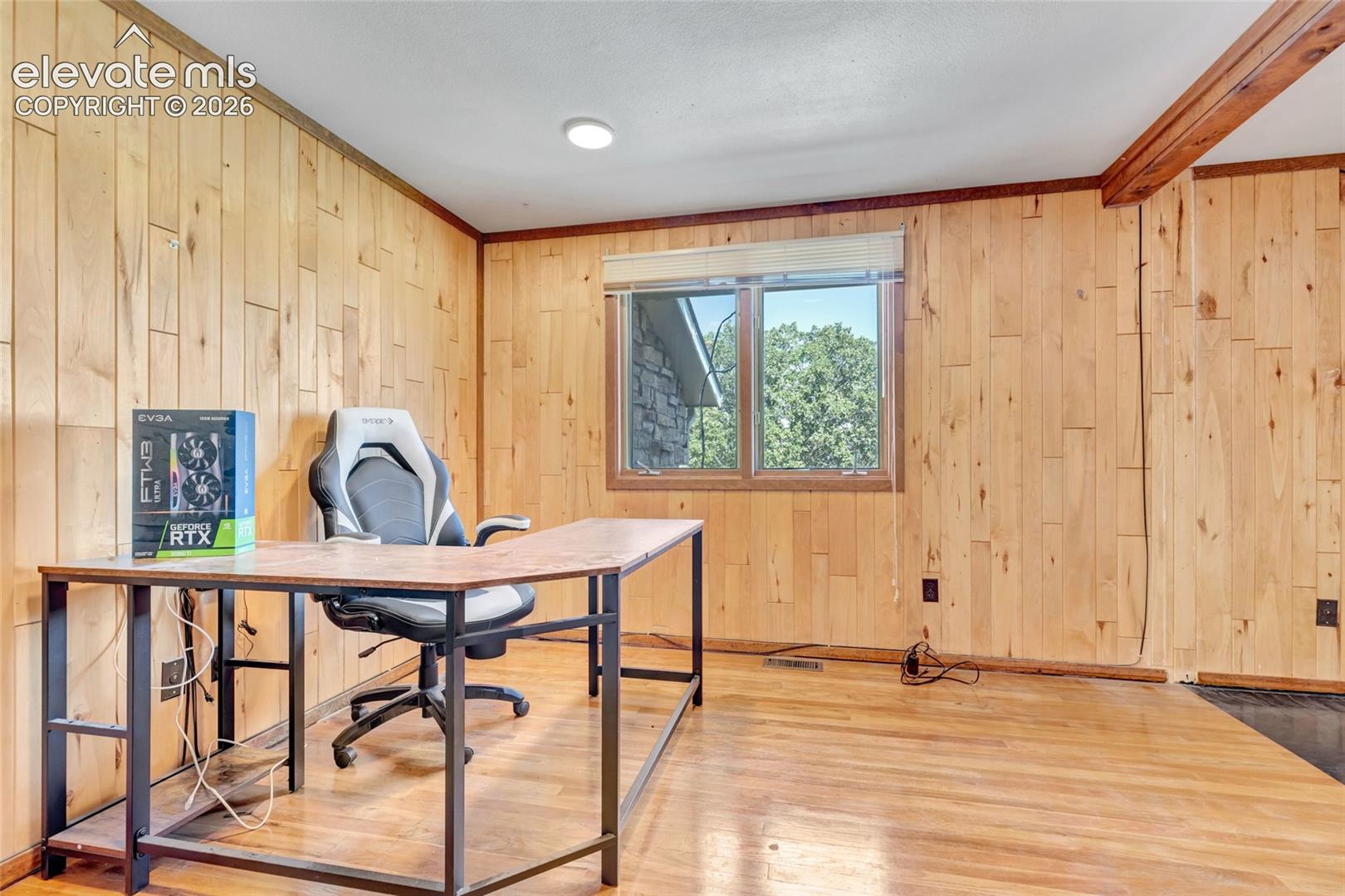 Wood-paneled walls, wood-finish flooring, a wood-framed window, and exposed wood beam