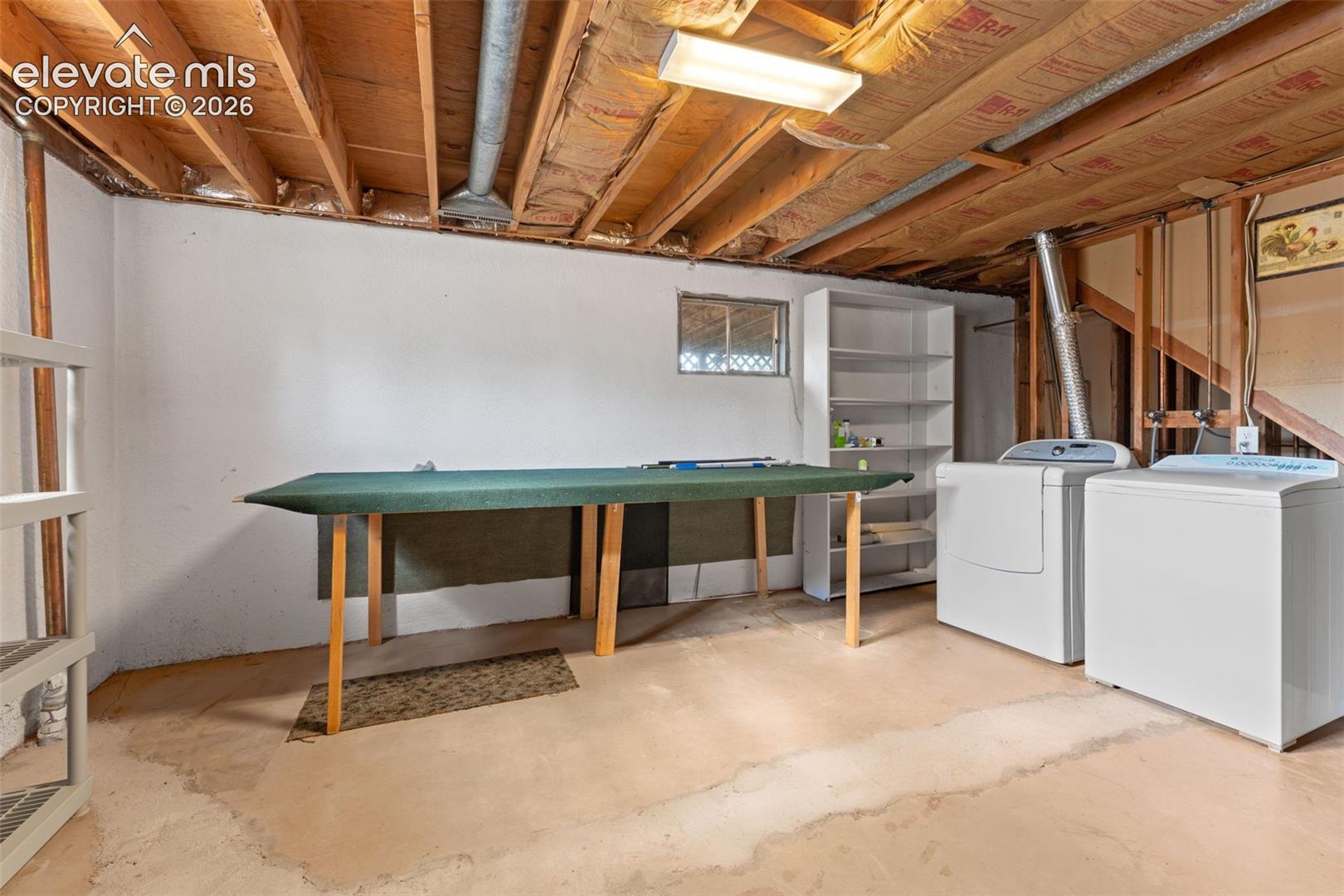 Unfinished basement featuring exposed wood joists, concrete flooring, and white painted walls