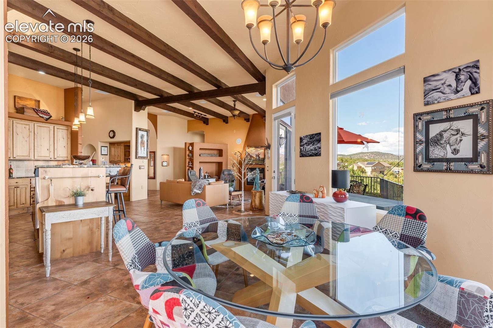 Exposed wood ceiling beams, oversized windows, tile flooring, built-in fireplace, and custom hanging light fixtures