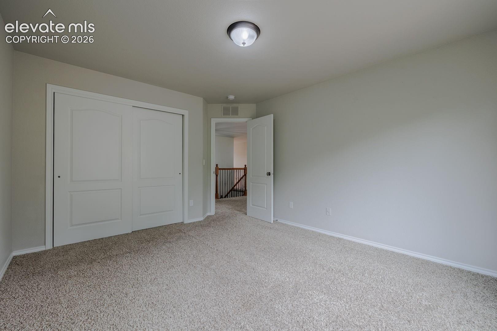 Carpeted interior room featuring a flush mount ceiling light fixture, white trim, and a white interior door