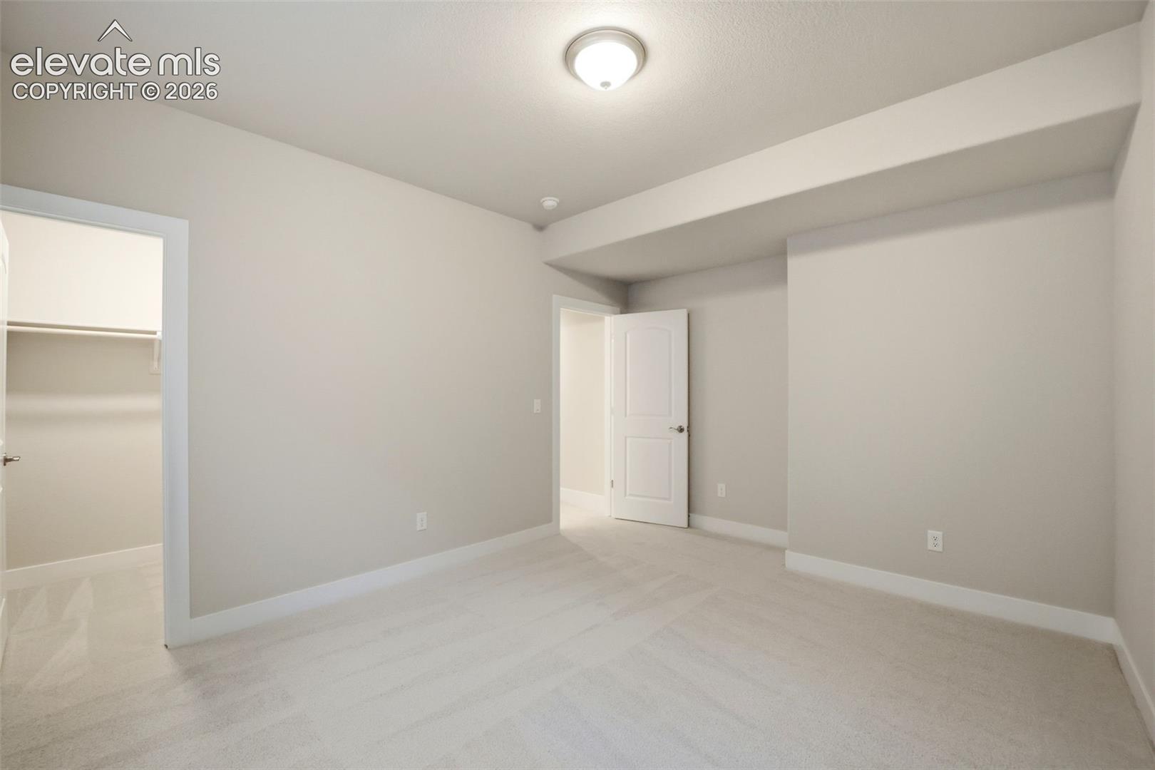 Room with neutral wall color, plush carpeting, ceiling-mounted light fixture, and an interior door opening to a closet