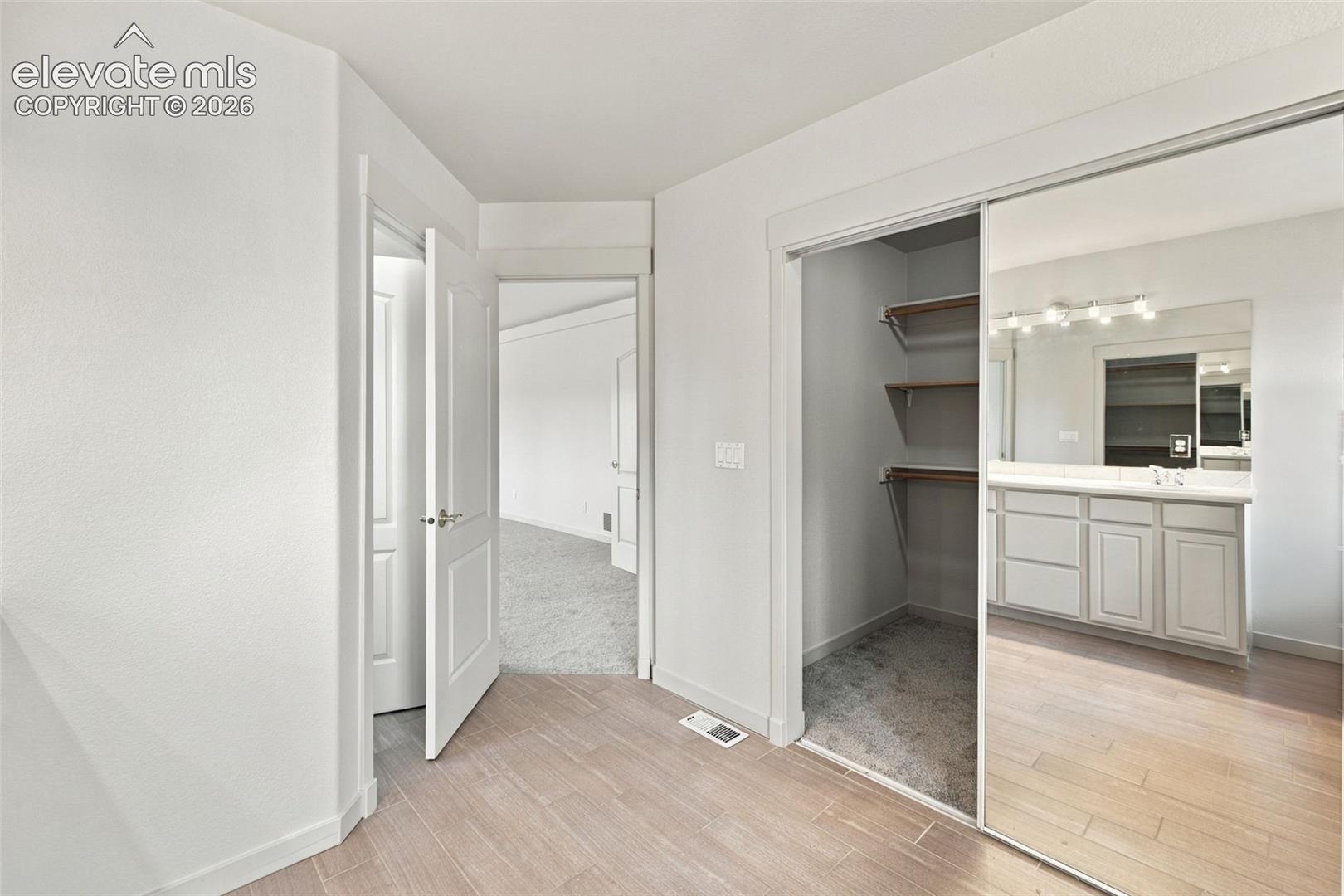Wood-finish flooring, sliding mirror-panel closet doors, and custom built-in shelving
