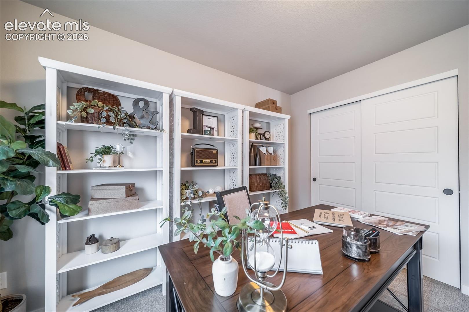 Dedicated workspace featuring multiple built-in shelving units, a large wood-finish desk, and sliding panel closet doors
*Photos of a model home*