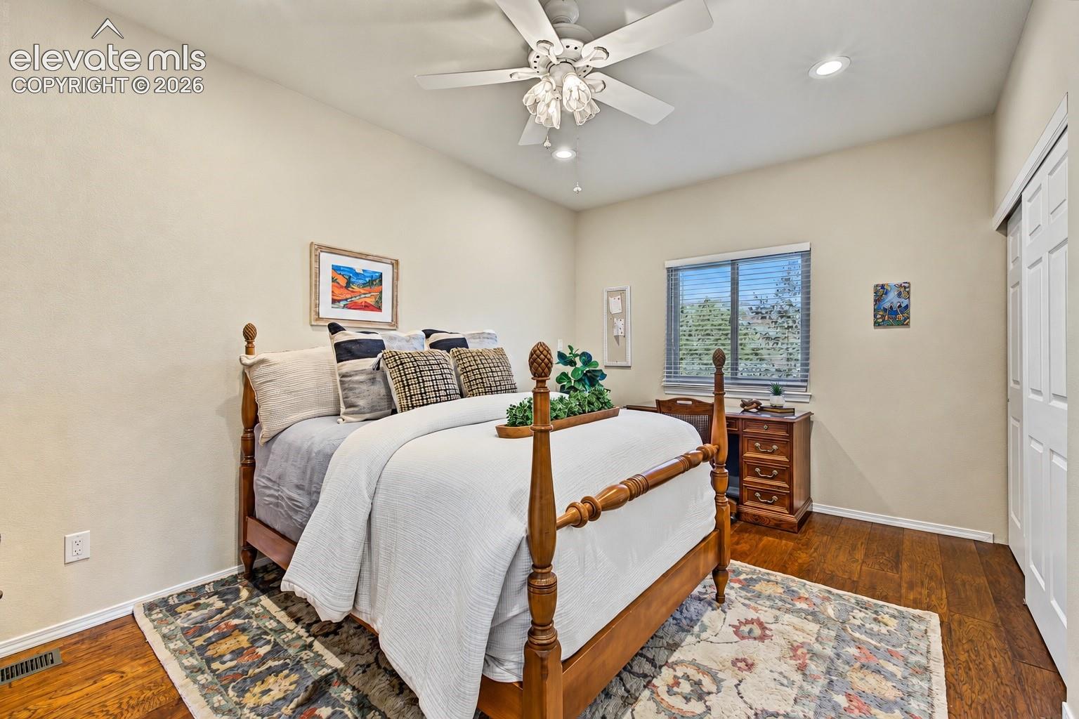 Additional main-level bedroom located on the opposite side of the floor plan from the primary suite, featuring hardwood flooring, a ceiling fan, recessed lighting, a large window, and a spacious closet.