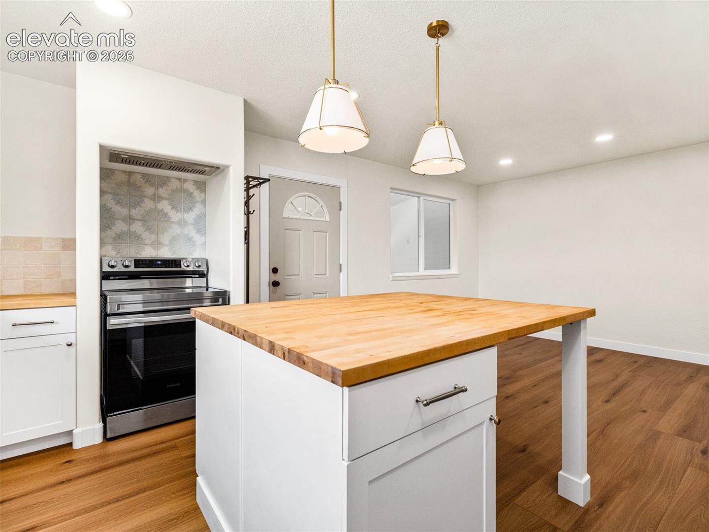 This is the kitchen in the ADU with LVP, Butcher block counter tops, gold accessories, stainless appliances and tile back splash