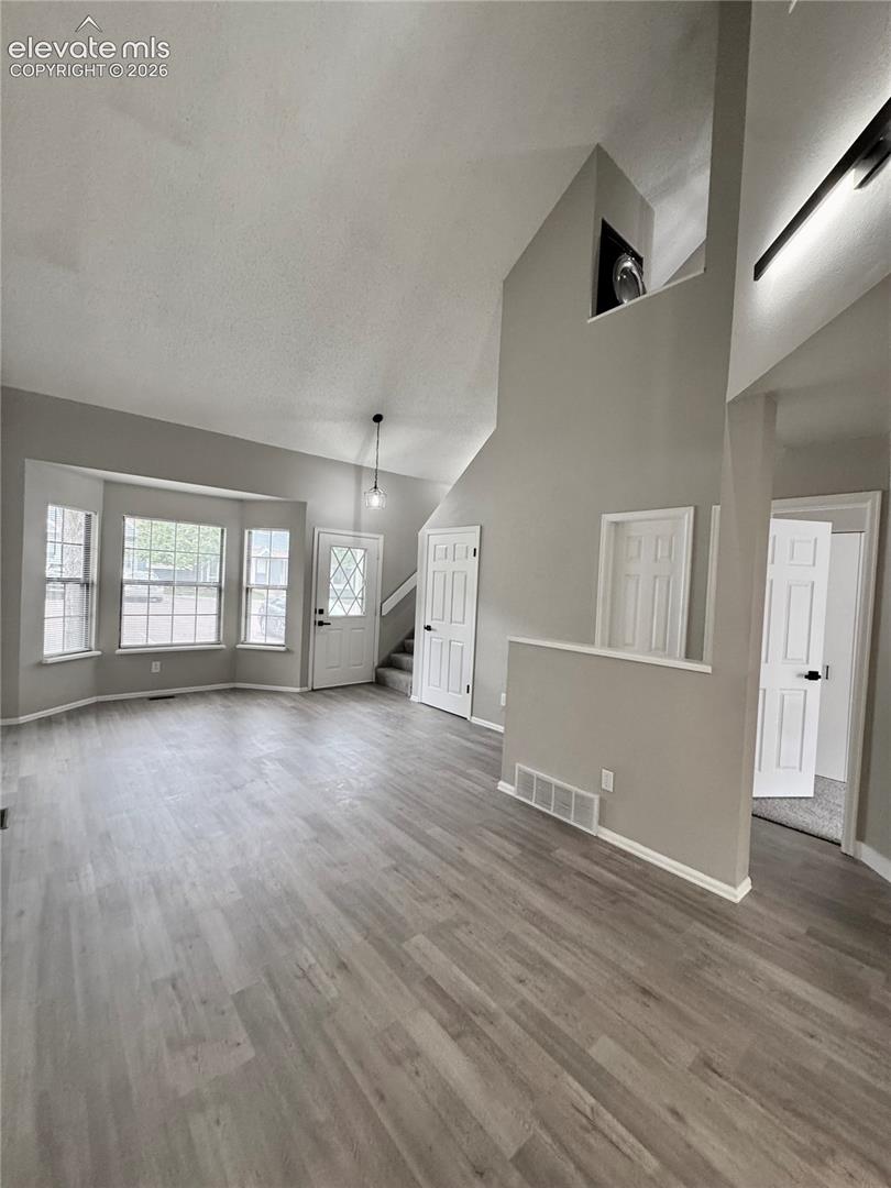 Vaulted ceiling, wood-finish flooring, bay windows, multiple doors, and a decorative wall niche