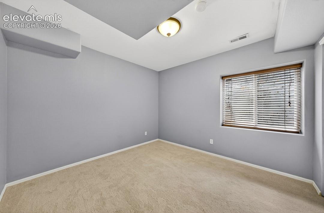 Room featuring neutral wall tones, plush wall-to-wall carpeting, a recessed ceiling accent, and a dual-pane window with installed horizontal blinds